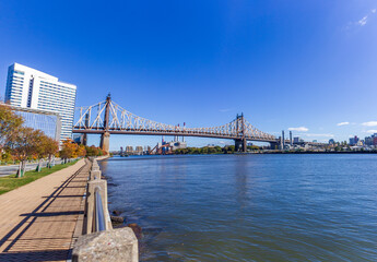 A picture of Ed Koch Queensboro Bridge in New York City, USA. In the picture one can see the East River, the Roosevelt island, Brooklyn and Domino Sugar Refinery and park