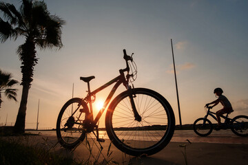 Silhouette of a bike at sunset. The sun shines through the frame of a bicycle