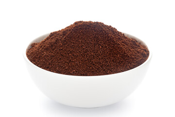 Close-Up of organic dark brown coffee granules in white ceramic bowl over white background