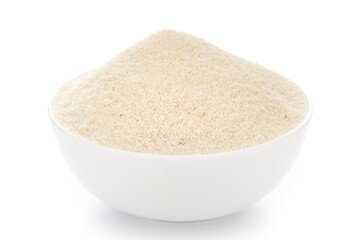 Close-Up of organic fine semolina granules in white ceramic bowl over white background