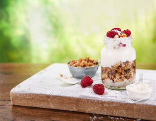 Greek yogurt, granola, parfait fresh raspberries, coconut in a glass on wooden table outdoors. Summer Healthy, summer breakfast.