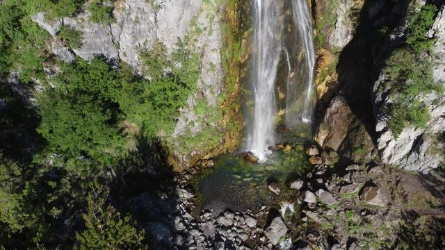 Beautiful Theth waterfall near Theth village in Albanian alps mountains. Majestic cascade waterfall into the forest in slow motion, Accursed mountains, Albania