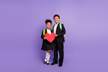 Photo of two african people kids hold red heart love symbol wear rucksack uniform isolated purple...