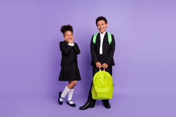 Photo of two cheerful african people schoolchildren boy help girl carry bag wear uniform isolated...