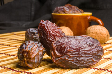 Big luxury dried date fruit in bowls on the bamboo mat, kurma ramadan kareem concept, close up.