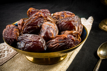 Big luxury dried date fruit in bowls on a linen napkin, kurma ramadan kareem concept, close up.