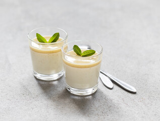Creamy pudding gooseberry with sauce in a glass on a light gray background