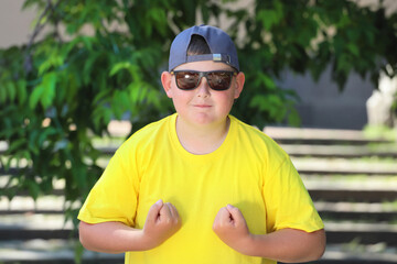 fat European boy in a yellow T-shirt shows muscles