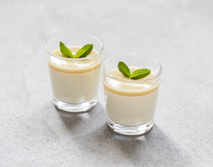Italian dessert Panna Cotta gooseberry with sauce in a glass on a light gray background
