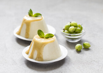 Vegan dessert, creamy gooseberry pudding with sauce on a platte on a light gray background