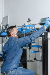 Male industrial worker with protective mask, blue latex gloves and overall working with industrial machinery