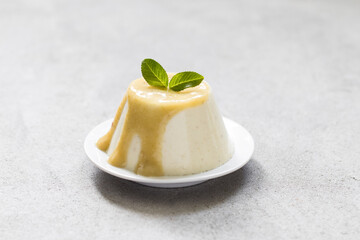 Italian dessert Panna Cotta gooseberry with sauce on a platte on a light gray background