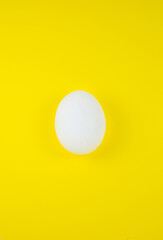 White egg on the yellow background. Copy space. Minimalism, original and creative photo. Beautiful wallpaper. Easter holidays.