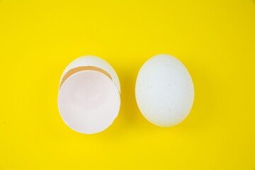 White egg and eggshell on the yellow background. Copy space. Minimalism, original and creative photo. Beautiful wallpaper. Easter holidays.