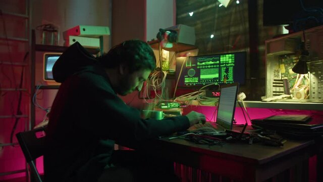 Angry hacker typing on keyboard at night, fail with breaking password, using laptop and bypassing cybersecurity. Young man developing program in dark room. Programmer infecting system with cyber virus