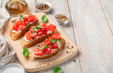 Bruschetta with tomatoes, feta and basil on a beige background. Italian appetizer, antipasti.