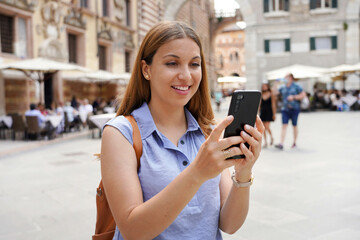 Young woman in blue shirt using telephone for video calling. Girl takes self portrait with smartphone in Verona, Italy.