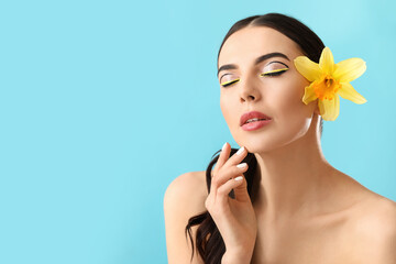 Fototapeta na wymiar Beautiful young woman with stylish makeup and flower on color background