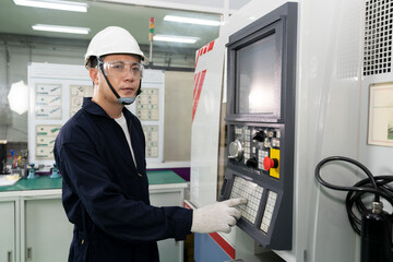 Asian technician engineer operating CNC machine in workshop.