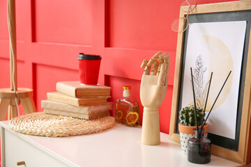 Wooden hand with houseplant and decor on shelf near color wall