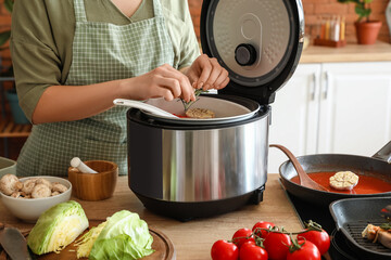 Woman using multi cooker in kitchen