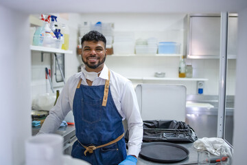 Worker in restaurant kitchen cleaning down after service