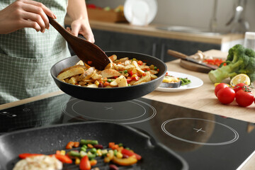 Woman frying potatoes with vegetables in kitchen