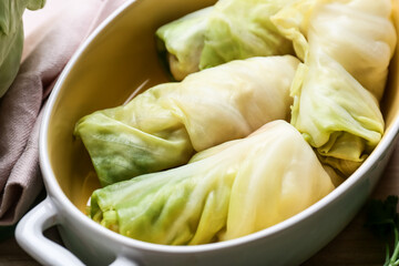 Baking dish with uncooked cabbage rolls on table, closeup