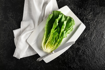 Plate with fresh romaine lettuce on dark background