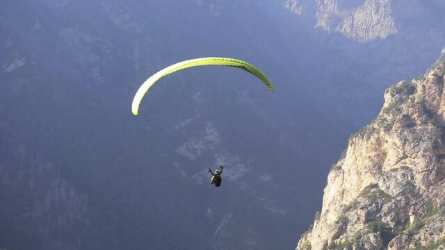 paraglider flying over mountains, summer day, healthy active lifestyle, paragliding