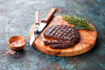 Homemade grilled beef burger or meat cutlet with Himalayan salt on a wooden board, selective focus
