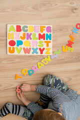Two year boy playing with wooden alphabet letters board on the floor. Intellectual game, preschool...