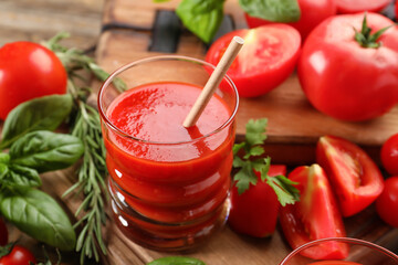 Glass of tasty tomato juice on wooden background