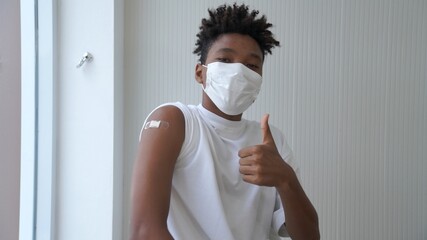 African American teenager showing COVID-19 vaccine bandage merrily in concept of coronavirus vaccination program to vaccinate citizen . - obrazy, fototapety, plakaty