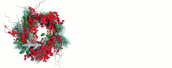 Long banner with a traditional Christmas wreath in red tones on a white background with copy space. Beautiful wreath with holly berries for festive new year 2022 header.
