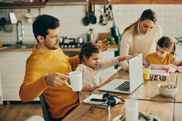 Small girl uses father's laptop while he's working from home.