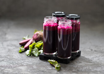 Drink, juice made from fresh beetroot in a tall glass bottle with a straw on a dark gray background