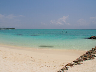 Fototapeta na wymiar Coast of an island in the Maldives with white sand and blue ocean. Copy space for text.