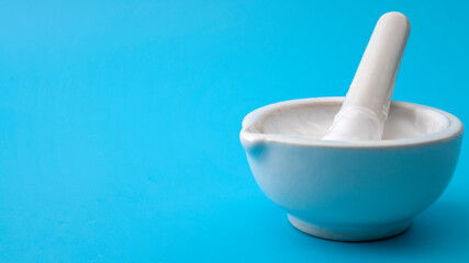 Skin care medication, dermatology lab research and skincare product testing concept with cream mixed with mortar and pestle in a blue laboratory background with copy space