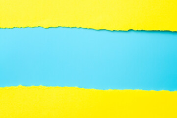 Notice, textured backgrounds and breaking news concept with torn yellow paper isolated on blue background with copy space