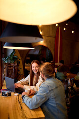 Portrait of young nice businesswoman and businessman at cozy cafe.freelance and remote work. caucasian woman and man work together, have talk, side view portrait