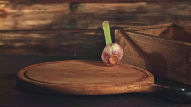 Super slow motion garlic falls on a cutting board on a wooden background. Filmed on a high-speed camera at 1000 fps. High quality FullHD footage