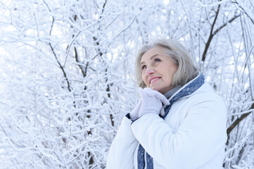 Portrait of happy beautiful senior woman posing in snowy winter park