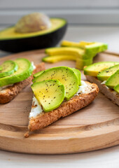 Tasty avocado sandwich with soft cheese, sliced avocado and pepper on toasted bread for breakfast or lunch. Clean eating or dieting concept. Homemade easy recipe of vegan food for everyday cooking.