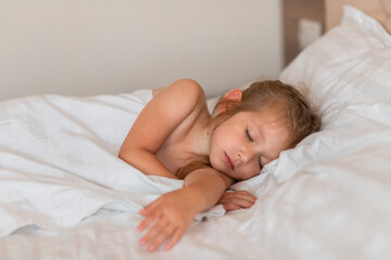 Fototapeta na wymiar Adorable little girl sleeping in bed with white linens. Place for your text. Healthy baby sleep.