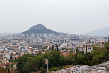 Obraz premium View on mount Lycabettus and Athens old city center with summer greenery in gray foggy day from Areopagus - Hill near Acropolis
