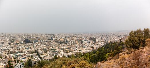Obraz premium Athens city center streets with white buildings on foggy day. Rooftop panoramic view from Filopappou Hill near Acropolis, Greece