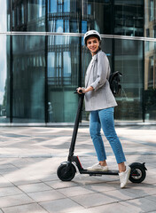 Stylish cheerful woman standing on electric push scooter and looking away © Artem Varnitsin