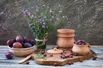 Still Life in a county style: gooseberry, plums and fresh mint on a wooden table. 
