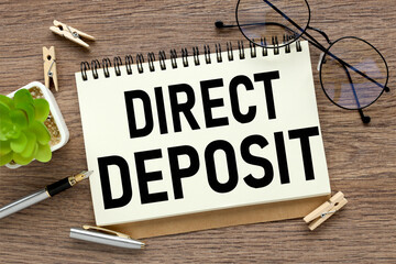 DIRECT DEPOSIT. notepad with text on a wooden table. notepad near a potted plant